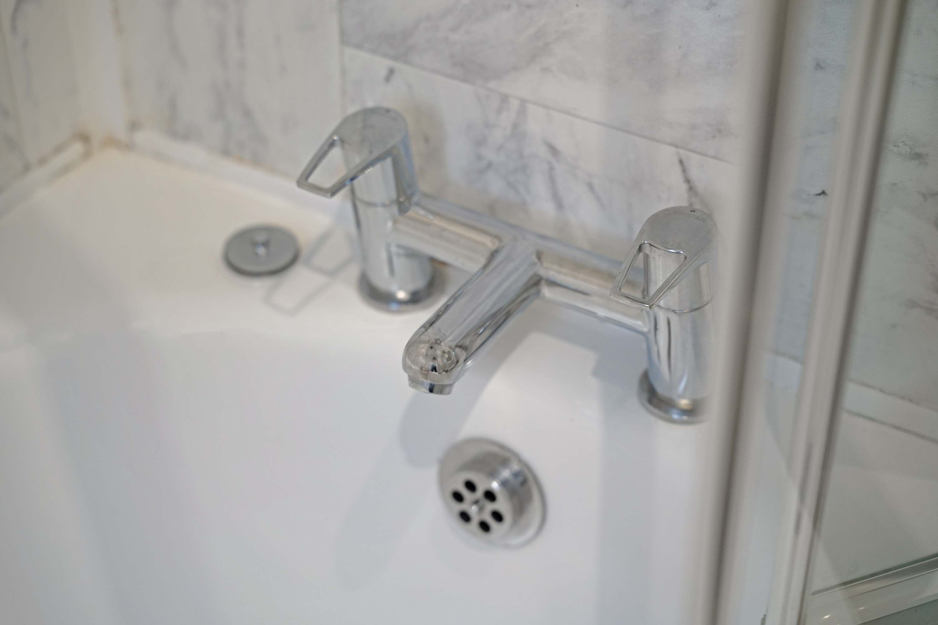 Ein modernes Badezimmer mit einer weißen Badewanne, Chromarmaturen und Marmorfliesen.