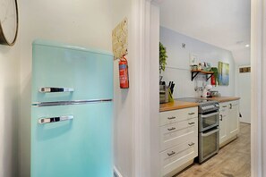 Una cocina con un refrigerador azul antiguo, un horno moderno y una encimera de madera.