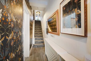 A hallway with a carpeted staircase, a welcome sign, and framed artwork on the walls. - Coastal 3-bed Home for Families Contractors (Redcar)