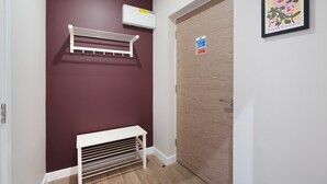 A hallway with a white bench, a white wall-mounted rack, and a wooden door with a fire action sign.