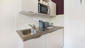A kitchen with a built-in microwave, a sink, and a toaster.