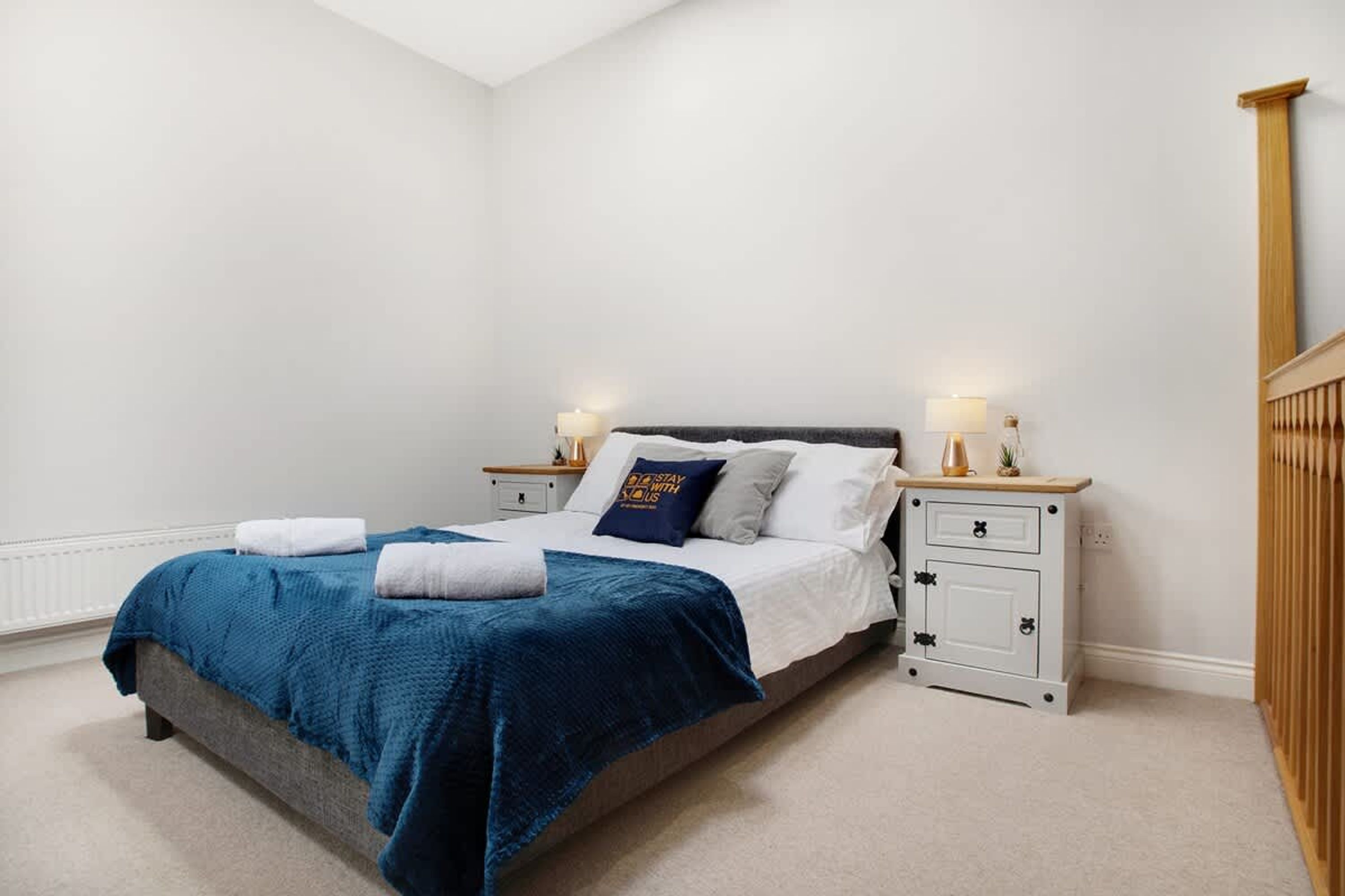 Une chambre à coucher comprenant un lit, des tables de chevet, une commode et une armoire en bois.