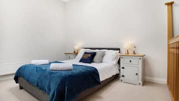 Un dormitorio con cama, mesitas de noche y un armario de madera.