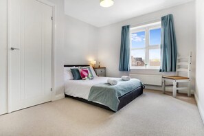 Ein Schlafzimmer mit einem Bett, einem Sessel, einem Fenster mit Vorhängen und einer Heizung.