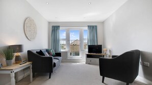 A modern living room with a sofa, two armchairs, a TV, and a dining table. - Duplex Apartment Close to A1 Private car Park (Darlington)