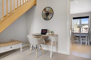 Ein Zimmer mit Schreibtisch, Stuhl und einer Uhr an der Wand.