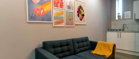 A living room with a grey sofa, a yellow throw blanket, and a wall with abstract art.