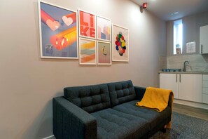A living room with a grey sofa, a yellow throw blanket, and a wall with abstract art.