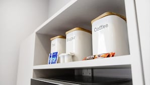 Una estantería de cocina con recipientes etiquetados para azúcar y café.