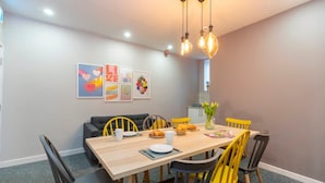Un comedor con una mesa de madera, sillas amarillas y un sofá negro.