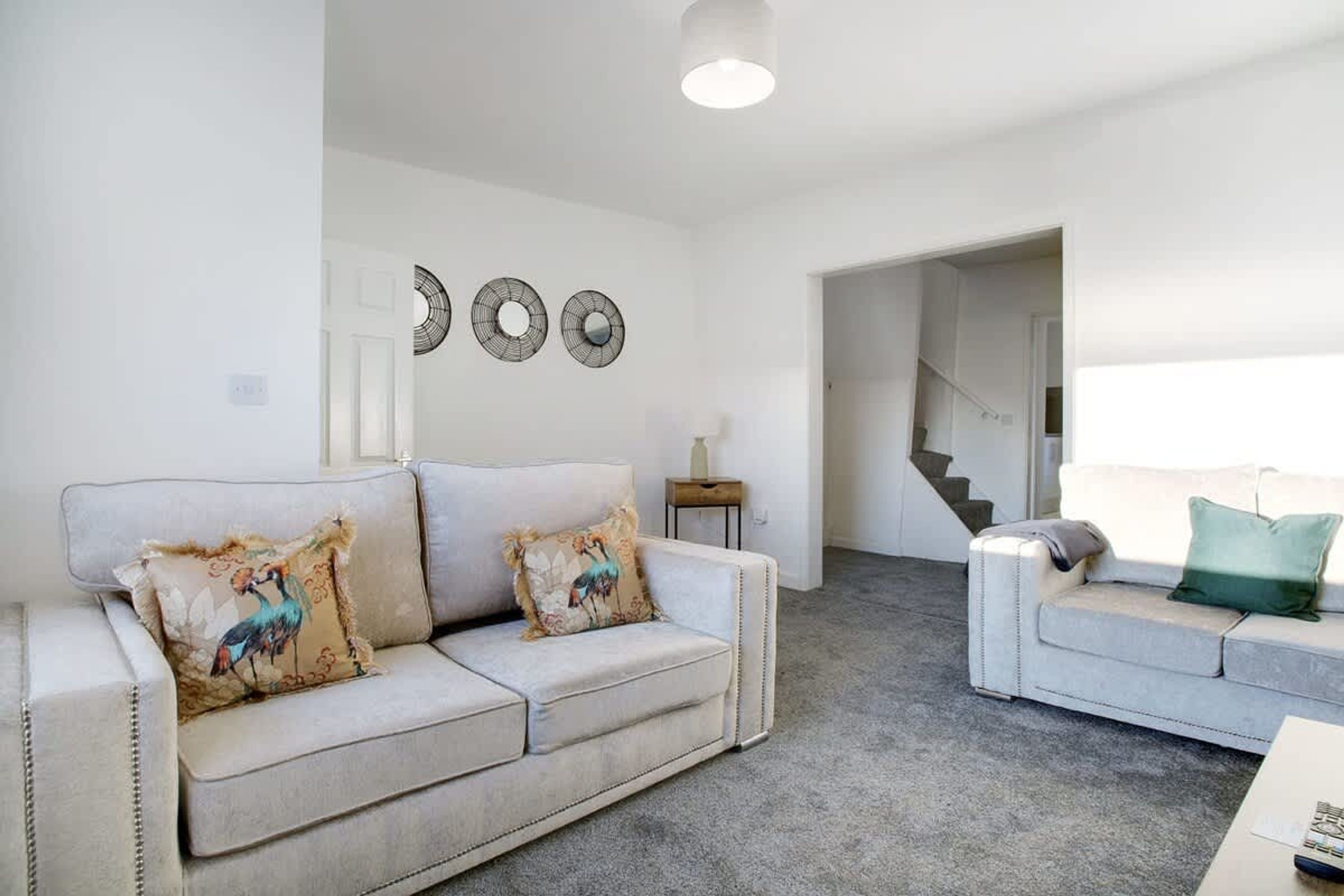 A living room with two sofas, a coffee table, and a staircase leading to another level.