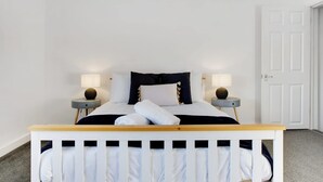 A bedroom with a bed, two bedside tables, and a door. - Family two Bedroom Home Free Parking and Backyard (Crook)