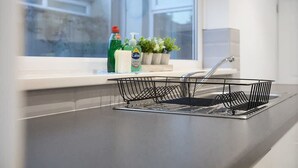 A kitchen with a window, a dish rack, and a plant on the windowsill. - Family two Bedroom Home Free Parking and Backyard (Crook)