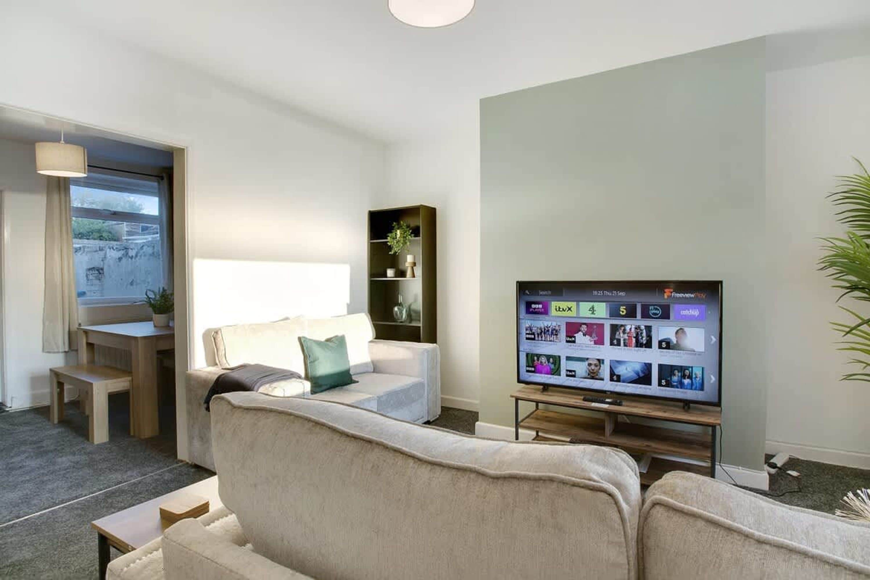 A modern living room with a sofa, a TV, and a small table.
