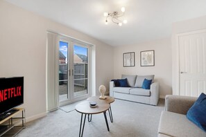 Un salon avec un téléviseur, un canapé, une table basse et une porte.