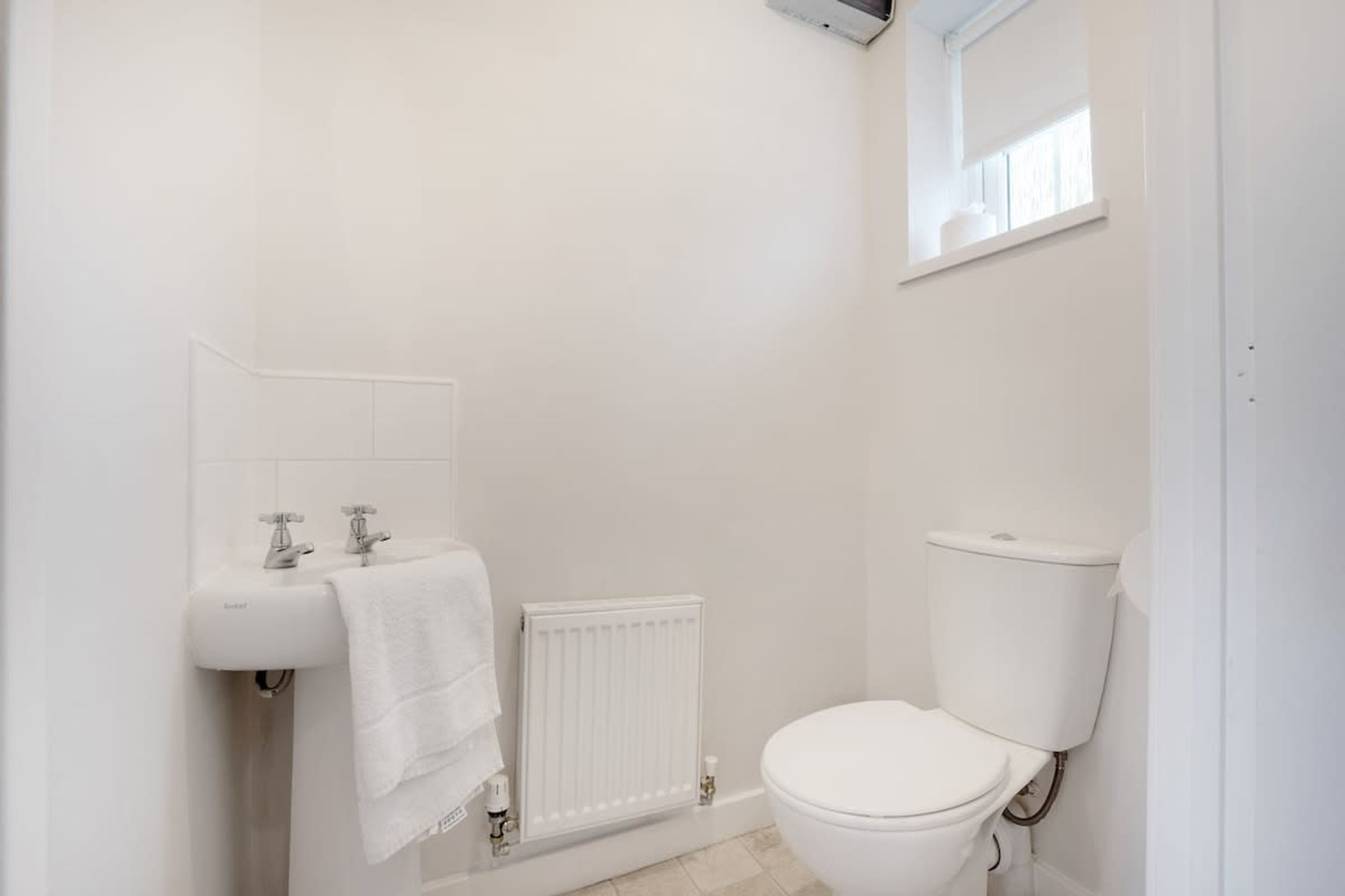 A small, clean bathroom with a toilet, a sink, and a window.
