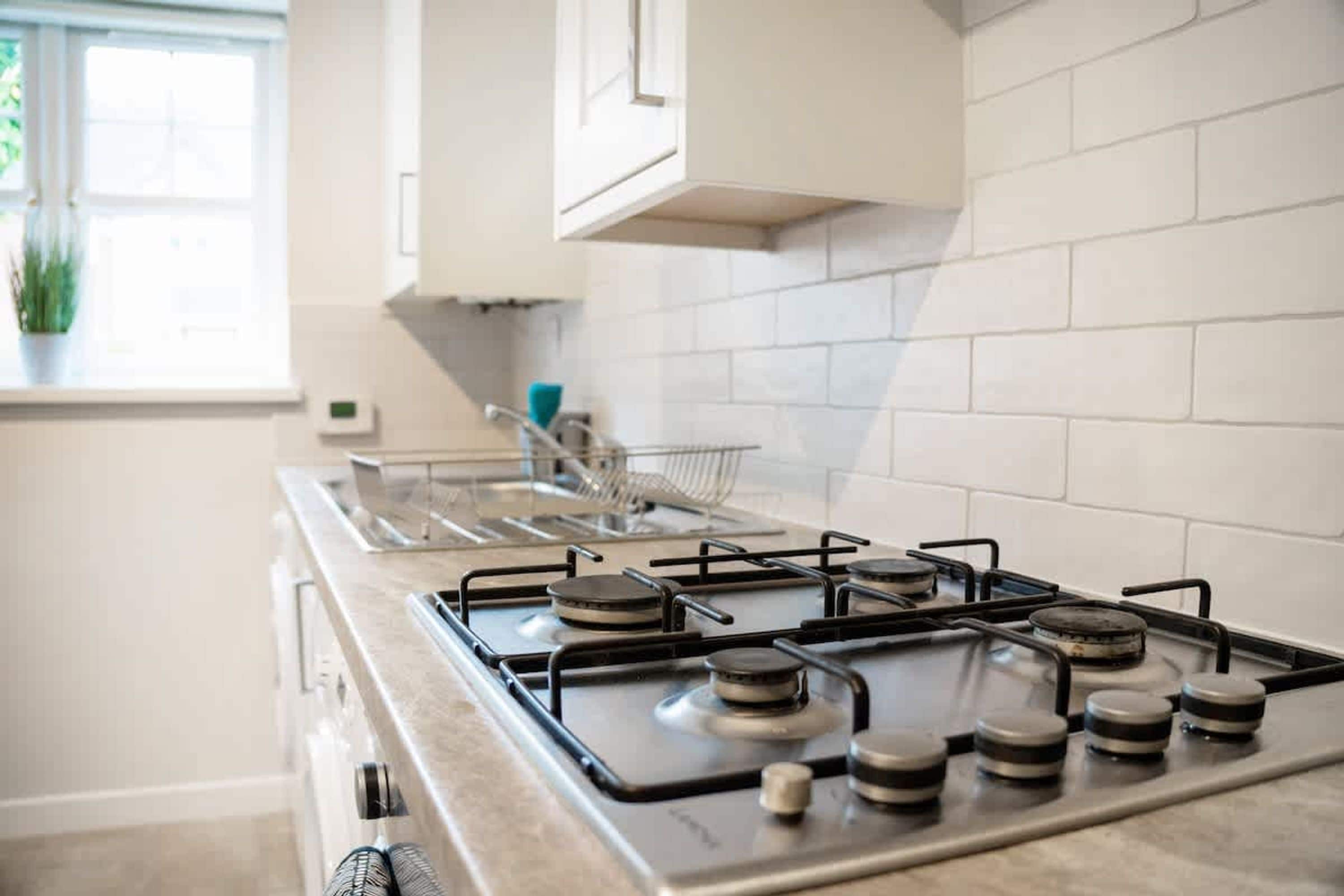 A kitchen with a gas stove, a sink, and a window with a plant.