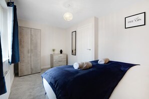 Ein Schlafzimmer mit Bett, Kleiderschrank, Schminktisch und einem gerahmten Bild an der Wand.