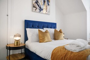 Ein Hotelzimmer mit einem großen Bett, einem Nachttisch mit Lampe und einem Gemälde an der Wand.