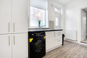 Una cocina moderna con armarios blancos, un lavavajillas negro y una ventana con una planta.