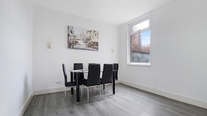 A dining area with a table and chairs, a painting on the wall, and a window with a view. - Classic 4 Bedroom Retreat Close to Infinity Bridge (Stockton-on-Tees)