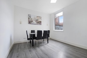 A dining area with a table and chairs, a painting on the wall, and a window with a view. - Classic 4 Bedroom Retreat Close to Infinity Bridge (Stockton-on-Tees)