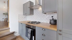 A modern kitchen with grey cabinets, a wooden countertop, a gas stove, and a slow cooker. - Central Newcastle 2BR With Free Parking and Wifi (Newcastle-upon-Tyne)