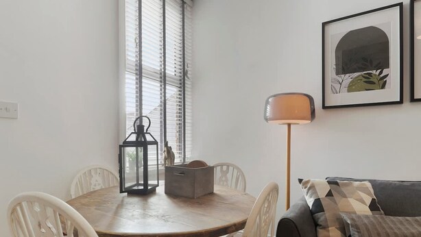 A dining area with a round table, chairs, a lantern, and a sofa with cushions. - Central Newcastle 2BR With Free Parking and Wifi (Newcastle-upon-Tyne)