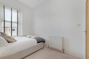 A bedroom with a bed, a radiator, and a window with blinds. - Central Newcastle 2BR With Free Parking and Wifi (Newcastle-upon-Tyne)