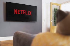 Un téléviseur à écran plat fixé au mur, avec le mot « NETFLIX » écrit en lettres rouges.