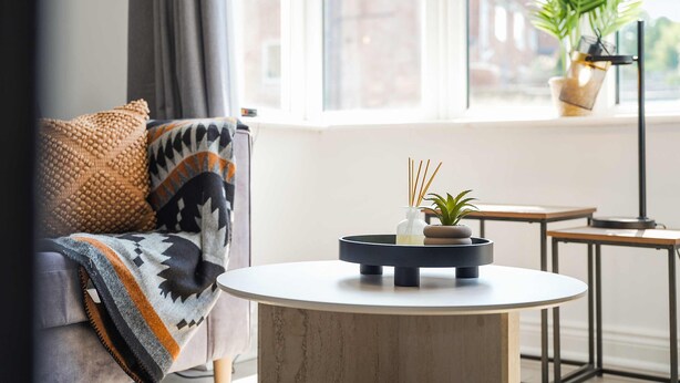 A modern living room with a sofa, a round coffee table, a small side table, and a potted plant by the window. - Stylish Hartlepool 3BR Sleeps 5 by Stay With Us (Stockton-on-Tees)