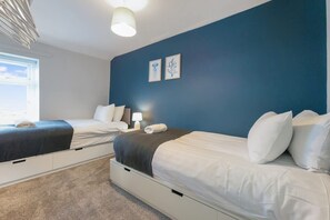 Ein Schlafzimmer mit zwei Betten, einem Fenster und einer Wand mit zwei gerahmten Bildern.