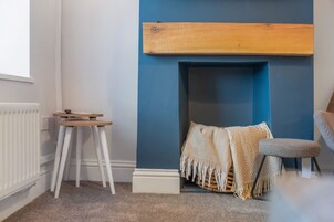 Una habitación con pared azul, radiador blanco, banco de madera y una pequeña mesa.