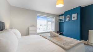 Ein Hotelzimmer mit Bett, Fenster, Schreibtisch und einer blauen Akzentwand.