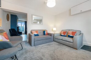 A living room with two grey sofas, a blue armchair, and a small table with a lamp. - Stylish 2 Bedroom in Bishop Auckland With Parking (Bishop Auckland)