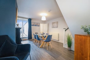 A modern loft-style room with a dining area, a large window, and a view of the outdoors. - Stylish 2 Bedroom in Bishop Auckland With Parking (Bishop Auckland)