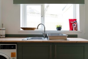 A kitchen with a window, a sink, a wooden bowl, a potted plant, and a fire extinguisher. - 4BR in Hill Top House With Free Parking and Wifi (Durham)