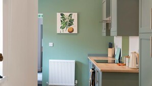 Eine Küche mit Heizkörper, Schränken, einer Arbeitsplatte und einer an der Wand befestigten Pflanze.