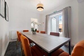 Una sala conferenze con un lungo tavolo, sedie arancioni, una pianta in vaso e una vista attraverso una porta in vetro.