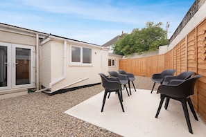 A patio area with a white floor, a wooden fence, and several black chairs. - 4BR in Hill Top House With Free Parking and Wifi (Durham)
