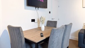 A conference room with a wooden table, grey upholstered chairs, a mounted television displaying 'NETFLIX', and a vase with dried plants. - Prime TS1 Location Walk to Shop Uni and Transport (Middlesbrough)