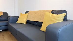 A dark blue sofa with three yellow cushions and a textured throw blanket. - Prime TS1 Location Walk to Shop Uni and Transport (Middlesbrough)