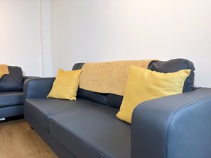 A dark blue sofa with three yellow cushions and a textured throw blanket. - Prime TS1 Location Walk to Shop Uni and Transport (Middlesbrough)