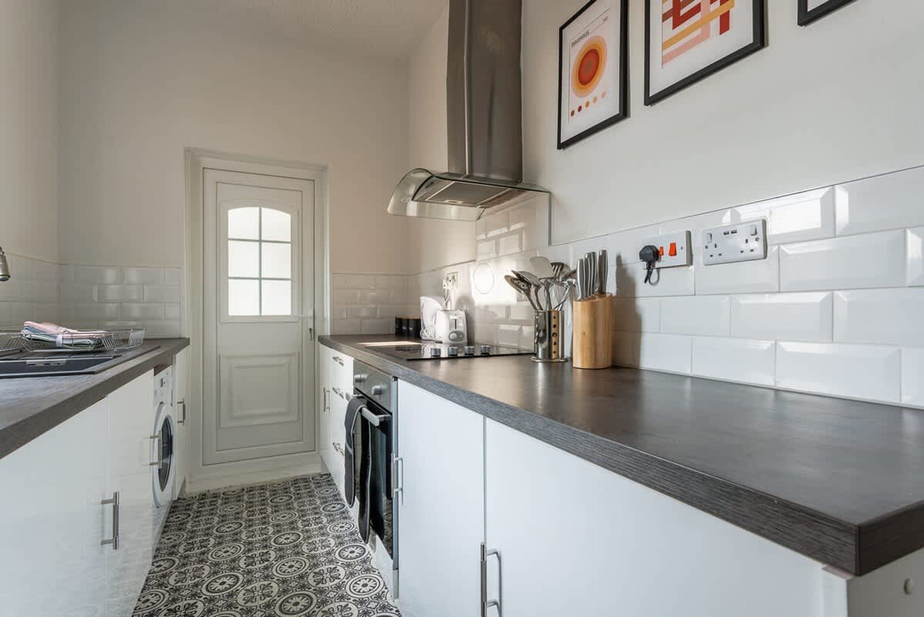 A modern kitchen with a built-in oven, a coffee machine, and a sink.