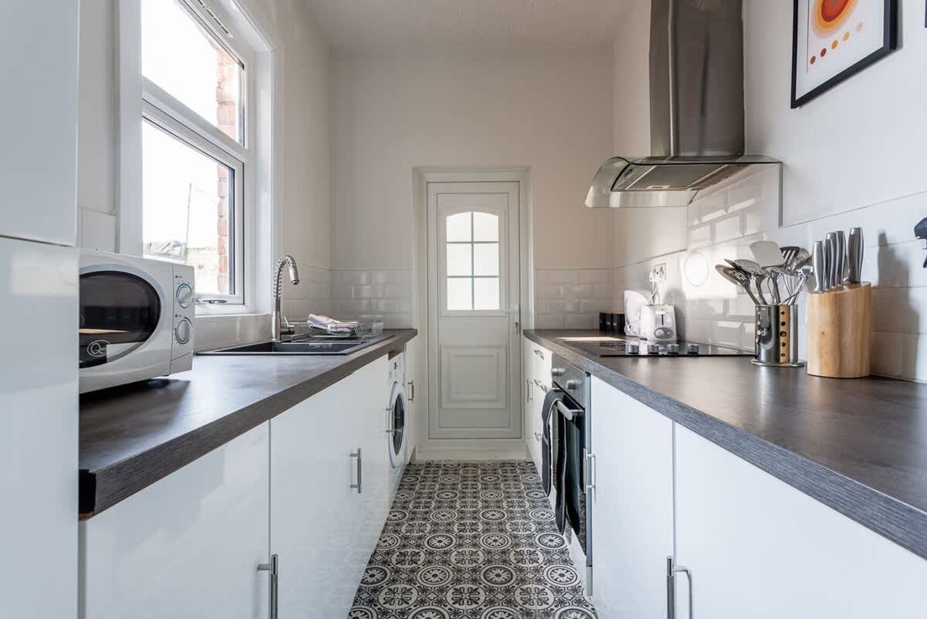 A narrow kitchen with a microwave, sink, and coffee maker.