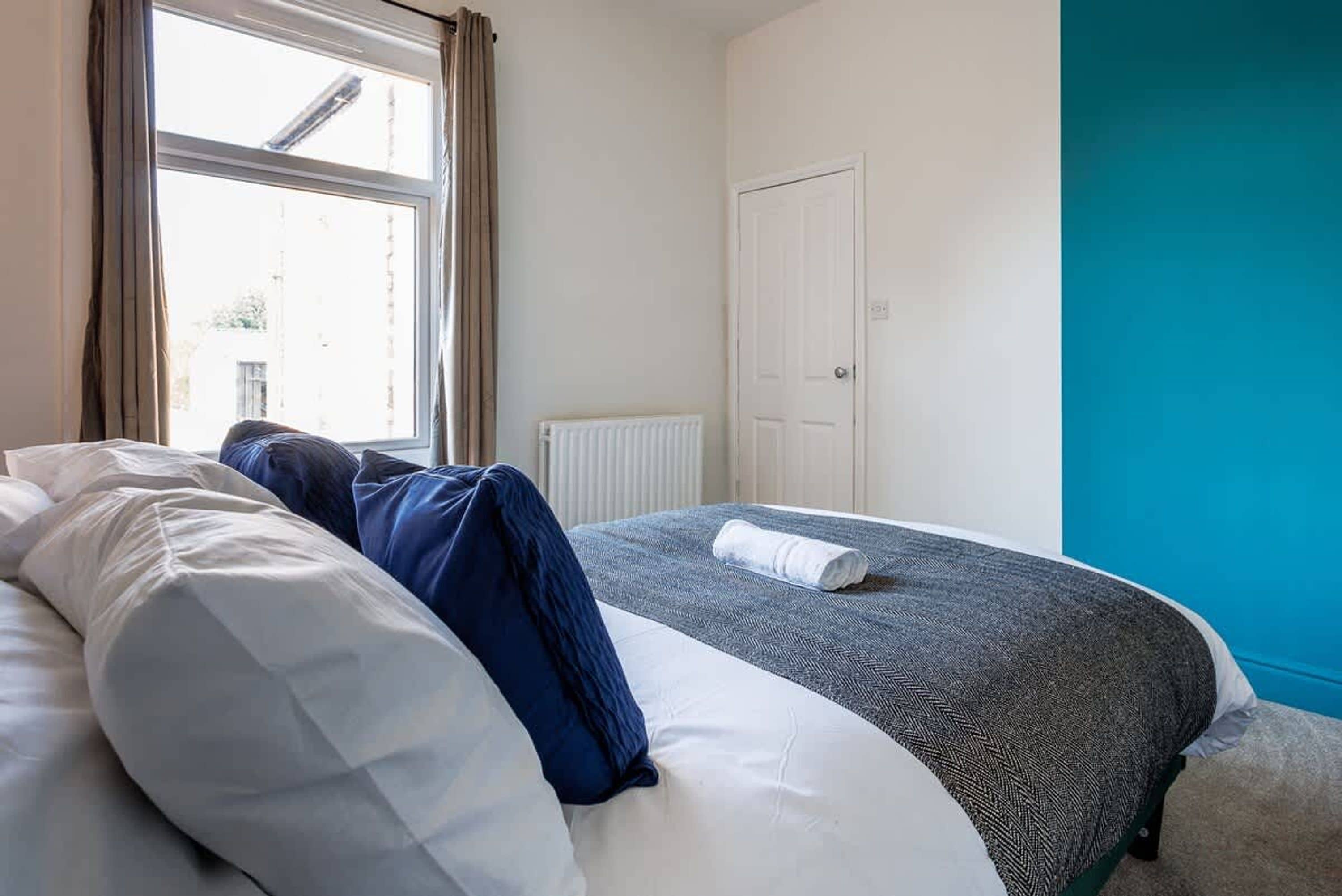 Een slaapkamer met een bed, een raam, een radiator en een deur.
