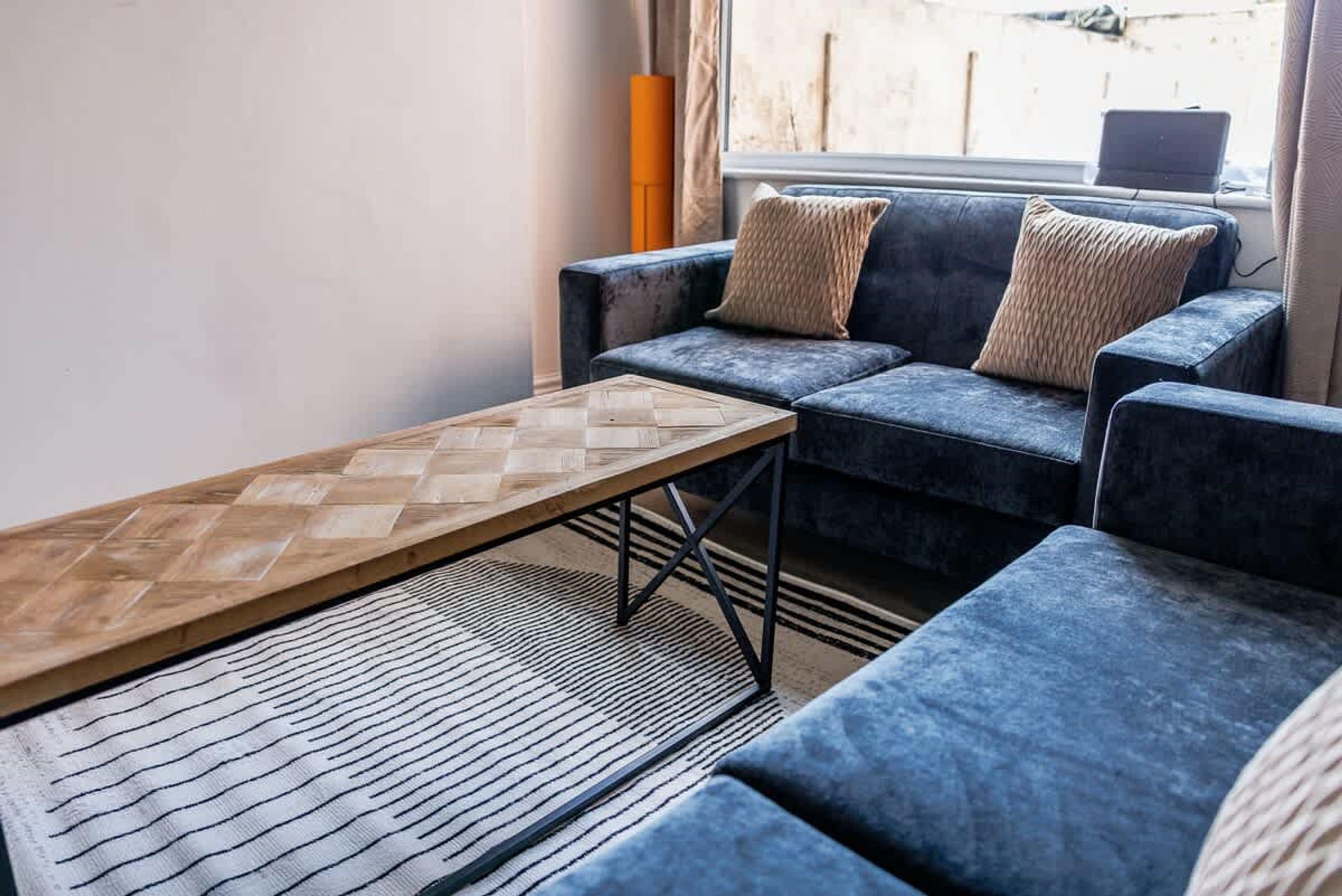 Una sala de estar con un sofá, una mesa de centro de madera y una alfombra estampada.
