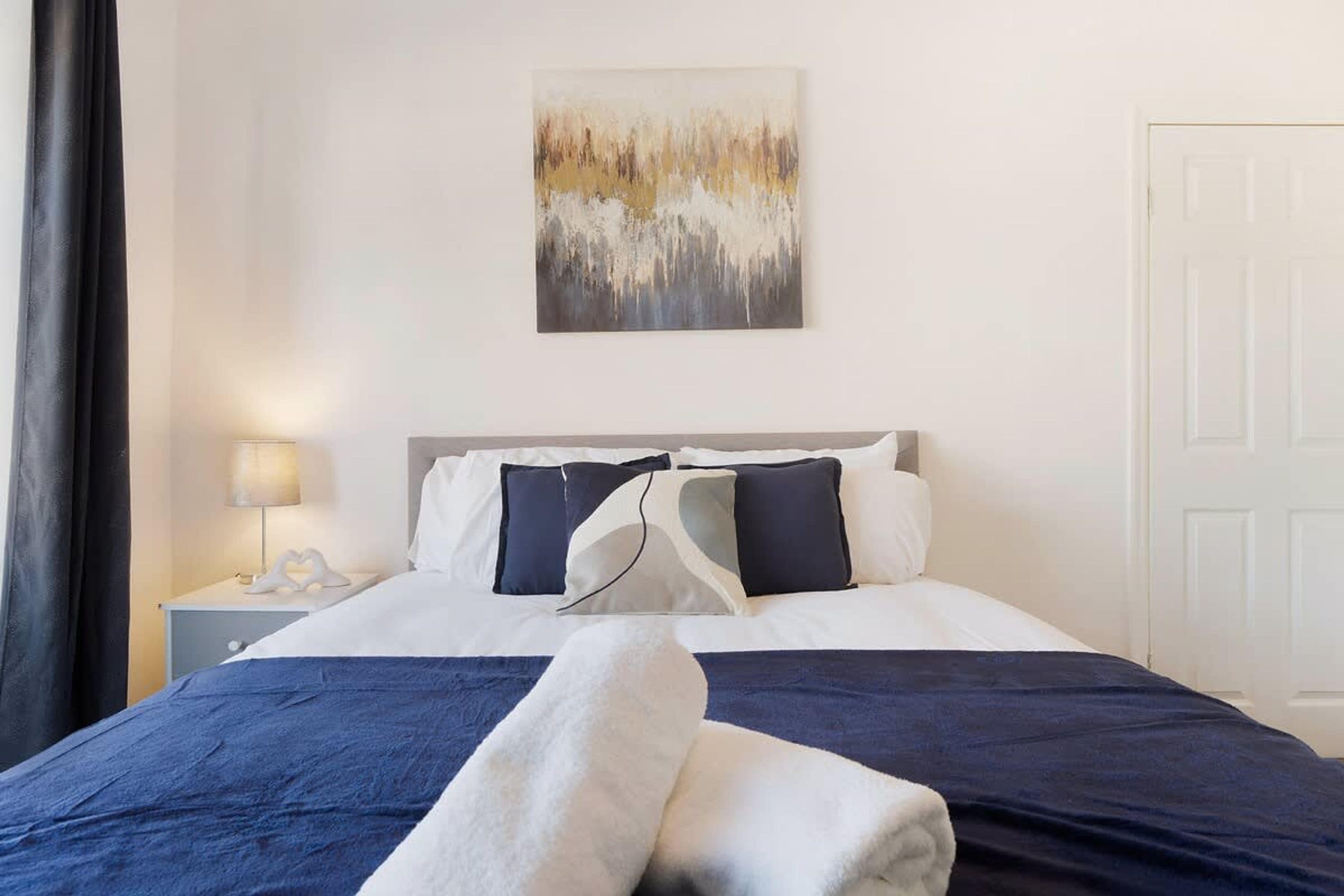 Una habitación de hotel con una cama, una mesita de noche, una lámpara y un cuadro en la pared.