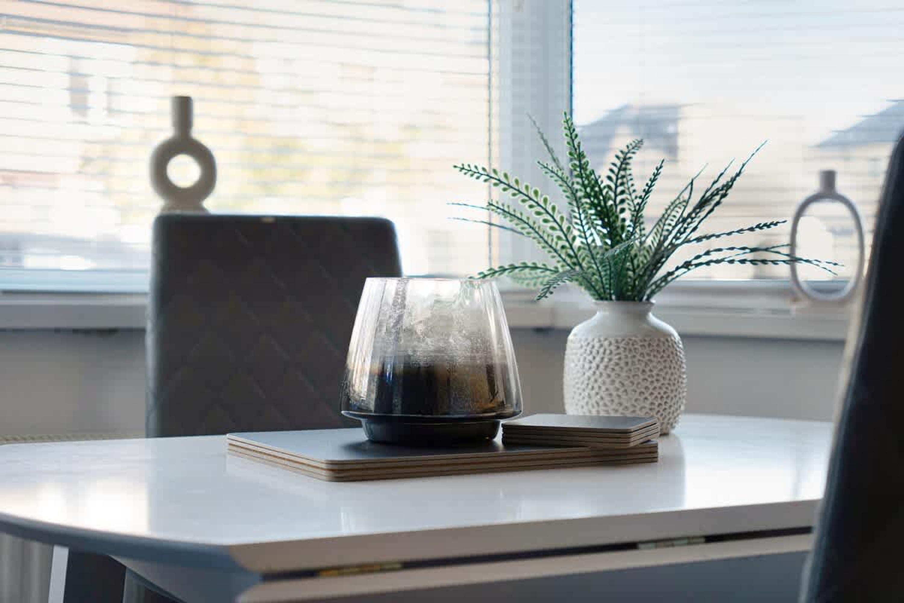 A table with a glass, a plant, and a stack of books.
