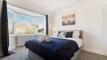 Habitación de hotel con una cama, una ventana con persianas, un cuadro en la pared y piso alfombrado.